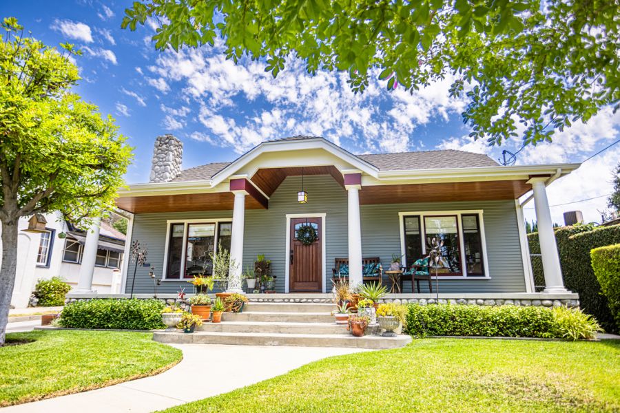 Freshly painted suburban home with front porch, steps, and landscaped lawn under a blue sky
